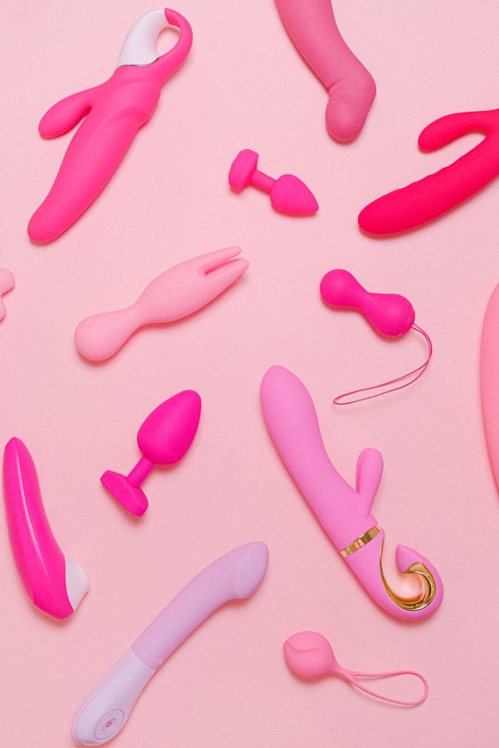 Explore a variety of pink adult toys including vibrators, silicone accessories, and more on a pastel background.